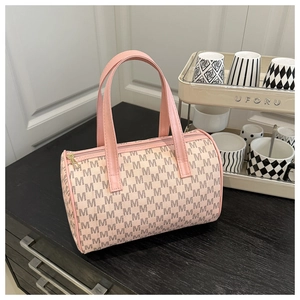 Dettaglio della borsa a cilindro vintage beige con manici rosa e monogramma