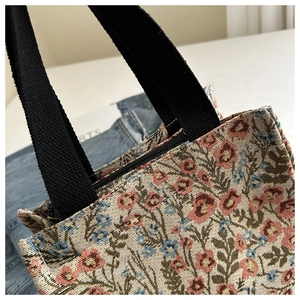 Close-up of vintage floral jacquard tote bag with black woven handles and zip closure