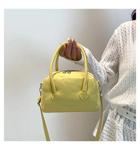 Détail du sac à main en cuir PU jaune avec poignées cylindriques et zip argenté