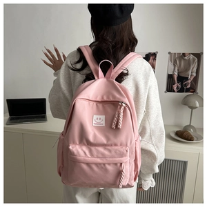 Pink nylon backpack for students featuring white smiley logo and braided rope zip pullers