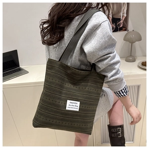 Détail du sac fourre-tout en velours côtelé vert foncé avec rayures et étiquette blanche