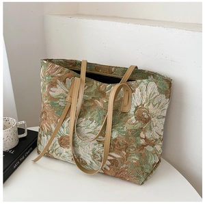 Detail of artistic floral jacquard tote bag with faux leather handles on a white table