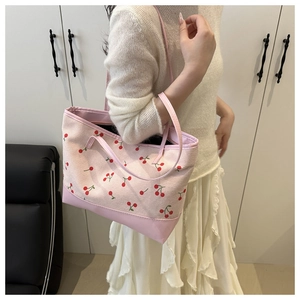Detail of cherry embroidery on canvas tote with pink leather base and shoulder strap