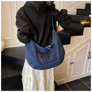 Detail of the oversized denim hobo bag featuring a frayed edge pocket and washed texture