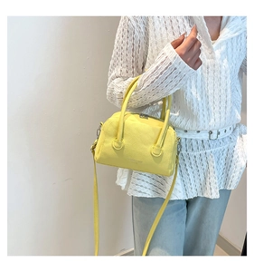 Détail du sac à main jaune en cuir grainé avec l'inscription FASHION & BAGS dessus