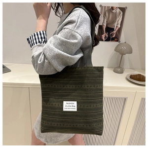Détail de la texture d'un sac cabas en toile rayée vert foncé avec étiquette de mode