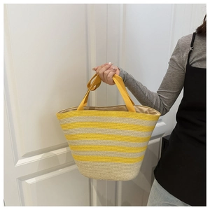Detail of yellow and white striped woven straw tote bag with sturdy canvas handles