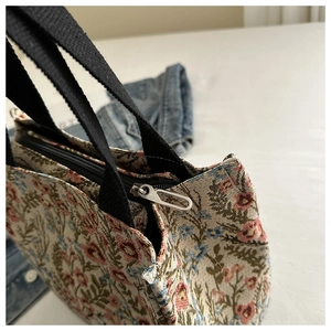 Close-up of floral tapestry tote bag showing silver zipper and thick woven fabric texture