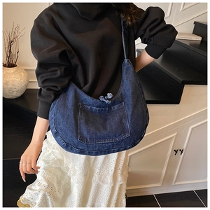 Detail of blue denim hobo bag with frayed front pocket and slim shoulder strap
