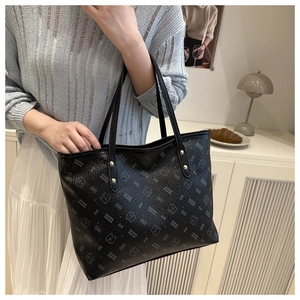 Detail of black tote bag with bear print and golden rivet accents in a lifestyle setting