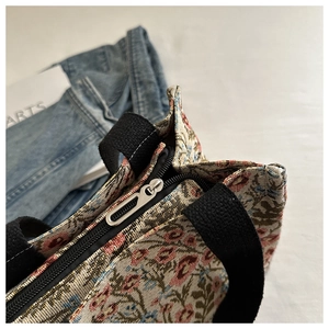 Close-up of floral jacquard tote bag showing silver zipper and woven texture details
