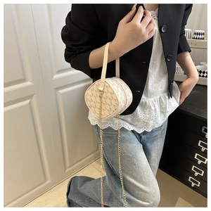 Detailed view of beige monogram crossbody bag with gold chain strap on a model