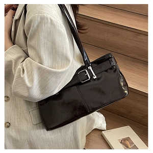 Close-up of a glossy dark coffee faux leather shoulder bag with silver metal buckle detail