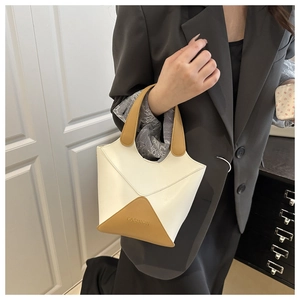 Gros plan d'un sac seau moderne pour femme en similicuir bicolore crème et marron.