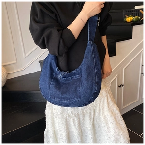 Close-up of blue denim hobo bag with front pocket and decorative drawstring bow