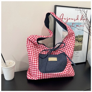 Close-up of red plaid canvas tote bag with denim pocket and bow tie drawstring detail