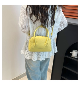 Detail of yellow lychee pattern PU leather handbag with ring handle and shoulder strap