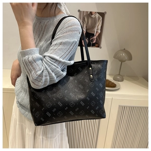 Detail of black tote bag featuring silver bear print and gold ring hardware on model
