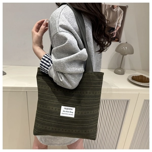 Détail du sac fourre-tout à rayures vert olive avec étiquette mode sur l'épaule