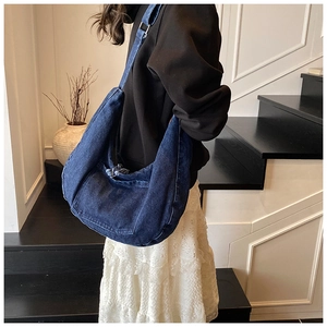 Detail of dark blue denim tote bag showing the washed texture and slouchy shoulder fit