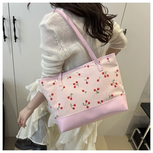 Pink corduroy tote bag with cherry print showing size and fit on model's shoulder