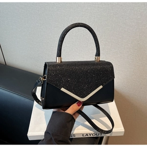 Close-up van elegante zwarte glitter crossbodytas met V-vormige metalen bies detail.