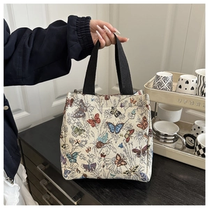 Detail of jacquard tote bag featuring butterfly patterns and durable black woven handles