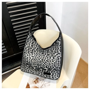Détail du grand sac cabas à imprimé léopard avec bordure noire sur une chaise moderne