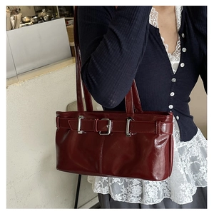 Close-up of burgundy patent leather handbag with silver metallic buckle detail