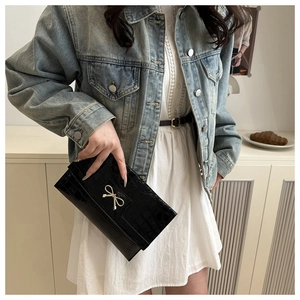 Close-up of black stone-patterned envelope clutch with elegant gold bow metal detail