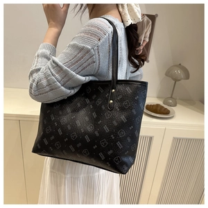 Detail of black tote bag with cartoon bear prints and textured leather on a female model