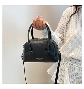 Detailed macro shot of black lychee-grain PU leather handbag with silver fashion logo