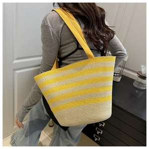 Detail of a large woven straw tote bag featuring yellow and beige horizontal stripes