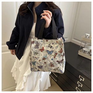 Close-up of vintage butterfly tapestry tote bag with woven fabric texture and black handles