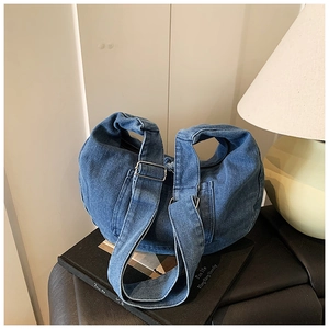 Detail of blue denim crescent bag with adjustable wide shoulder strap and metal buckle