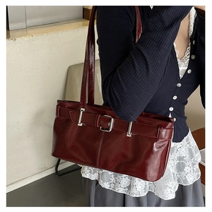 Deep red patent leather baguette bag featuring silver belt buckle detail and dual straps