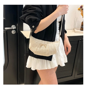 Detail of woven crescent crossbody bag with wave texture and gold bow ornament