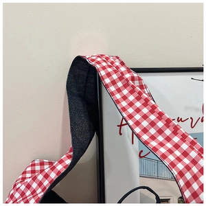Detail of red gingham pattern strap and navy blue canvas lining on a tote bag