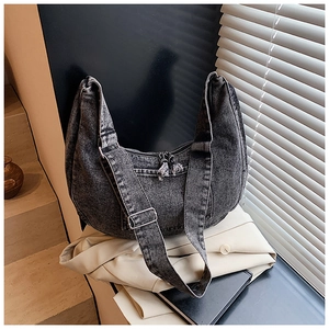 Detail view of large grey washed denim crescent crossbody bag with zipper and wide strap