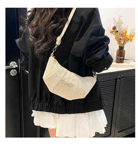 Detail of woven straw crossbody bag with golden bow and adjustable strap for women