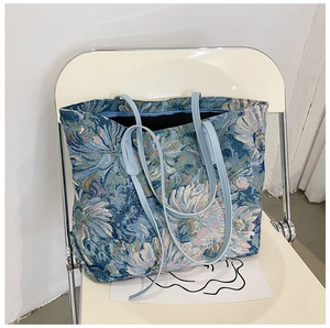 Close-up of blue floral jacquard tote bag texture and slim light blue shoulder straps