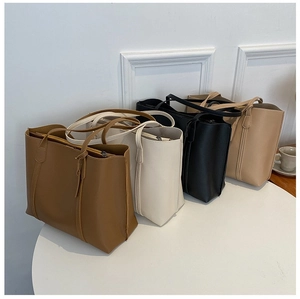 Top view of large leather tote bags in brown, white, black and beige on a minimal table