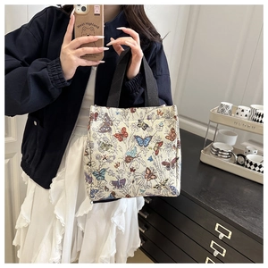 Detail of small butterfly jacquard tote bag featuring vibrant woven patterns and top handle