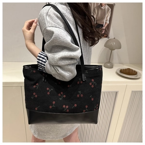 Détail du sac cabas noir en velours côtelé avec motif cerises et bandoulière en cuir lisse