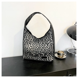 Gros plan détaillé d'un sac cabas léopard posé sur un bureau noir au style minimaliste