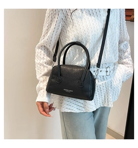 Détail du sac polochon en cuir noir avec texture grainée et boucles métalliques argentées