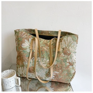 Detailed view of vintage floral jacquard fabric and synthetic leather straps on a tote bag