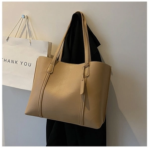 Detail view of khaki large capacity leather tote bag hanging in a minimalist setting