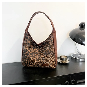 Sac fourre-tout léopard sur bureau noir avec lampe en métal et tasse à café