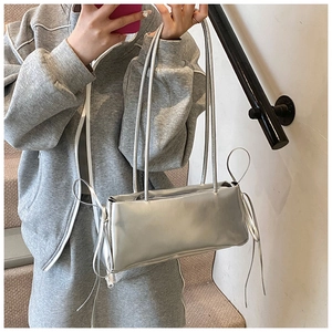 Silver metallic rectangular shoulder bag with bow drawstring on model in casual setting